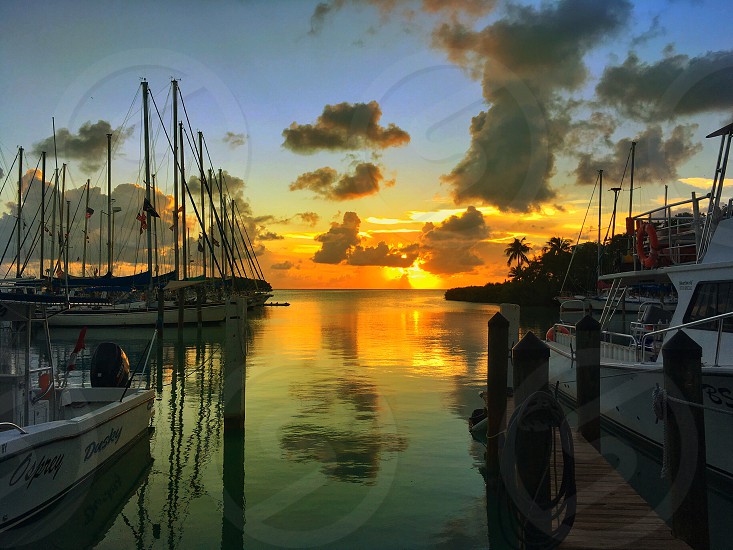 A sunset over the water with boats docked in it.