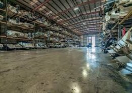 A warehouse filled with lots of shelves and a person standing in the middle.